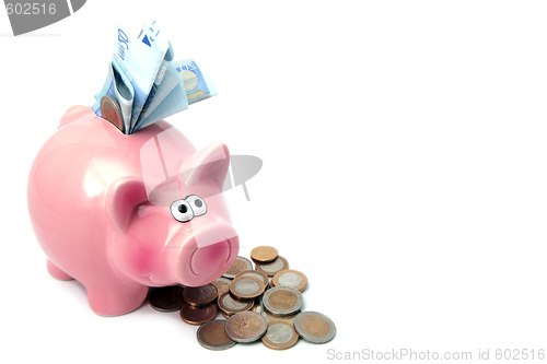 Image of Piggy bank stuffed with money and surrounded by coins.