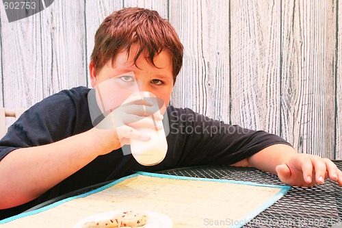 Image of Young boy eating cookies and milk