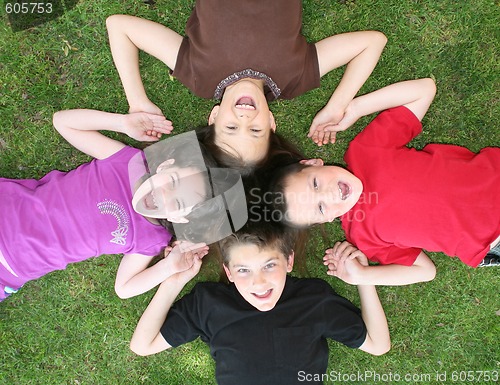 Image of Family of Siblings Lying on the Grass Laughing