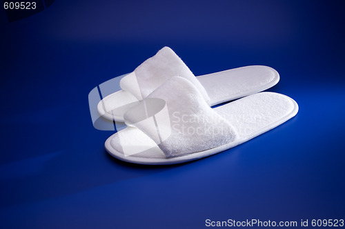 Image of White slippers on blue background