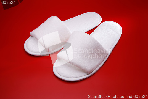 Image of White slippers on red background