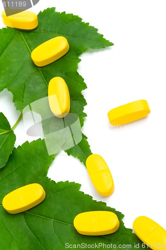 Image of vitamin pills over green leaves