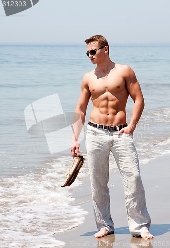 Image of Handsome man standing on beach