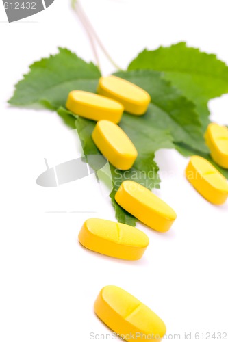 Image of yellow vitamin pills over green leaves