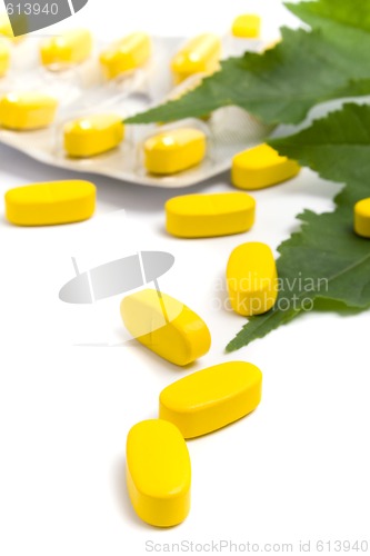 Image of yellow vitamin pills and green leaves