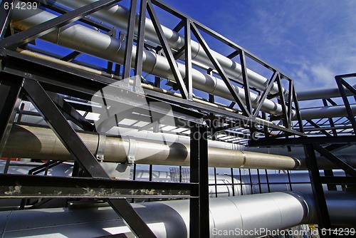 Image of industrial pipelines on pipe-bridge against blue sky