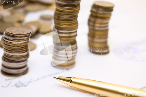 Image of Coins on  written contract  with pen