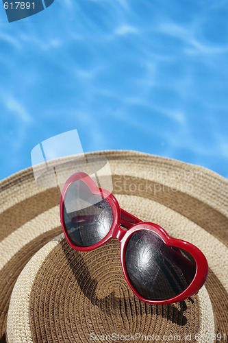Image of Red Sunglasses and Hat by a Blue Pool