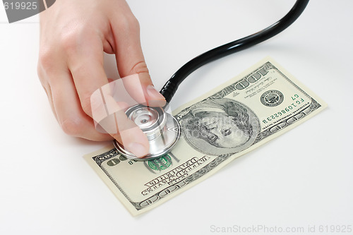 Image of Doctor holding stethoscope against one hundred u.s. banknote