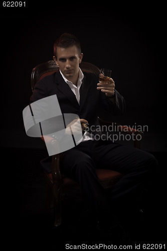 Image of Handsome young successful businessman smoking a cigar