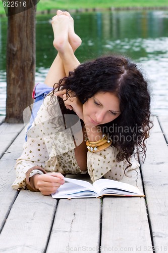 Image of outdoor portrait of a beautiful woman reading a book 