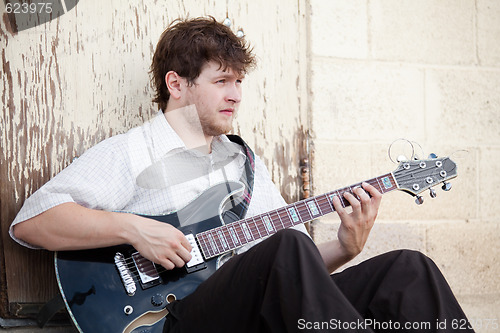 Image of young man playing guitar outdoors