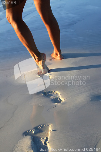 Image of Woman legs on sand with footprints