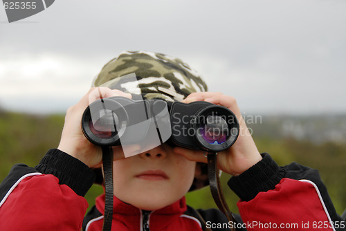 Image of boy observing nature through binoculars
