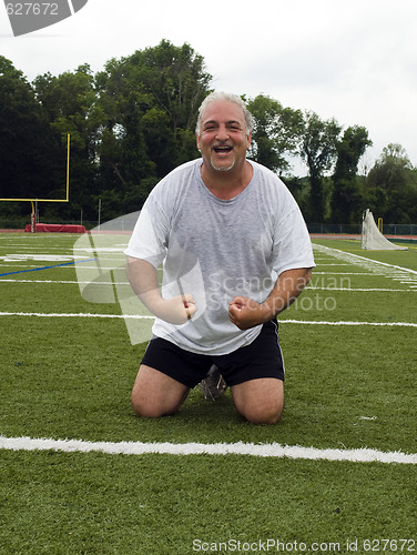 Image of middle age man stretching and exercising on sports field