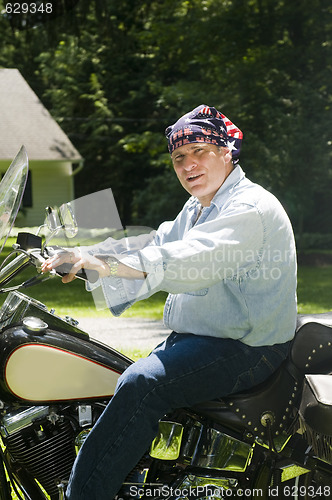 Image of middle age man on motorcycle with american flag bandana