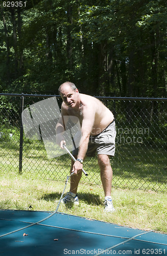 Image of homeowner removing swimming pool cover at suburban house