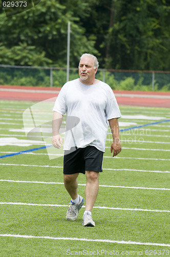 Image of middle age man exercising on sports field