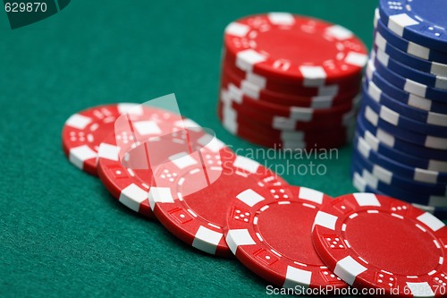 Image of Poker chips spread out over a green surface. 