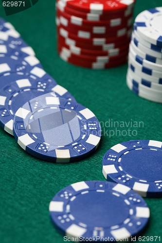 Image of Poker chips spread out over a green surface.