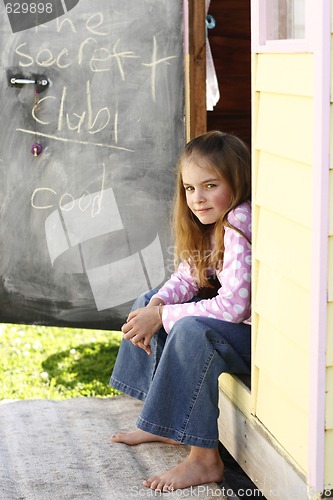 Image of Pretty young girl sitting at her playhouse.