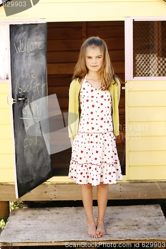 Image of Portrait of a pretty young girl standing outside her playhouse.