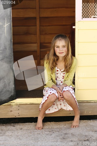 Image of Portrait of a pretty young girl sitting outside her playhouse.