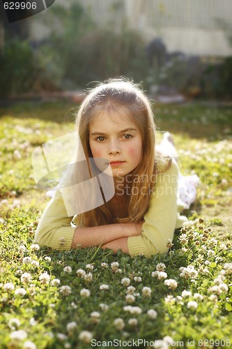 Image of A pretty young girl lying on the grass amongst flowers.