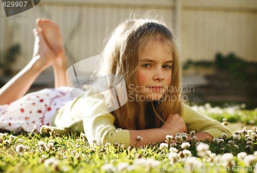 Image of Pretty young girl lying on the grass amongst flowers.