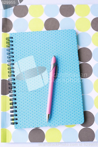 Image of Brightly colored notebook, folder and pen.