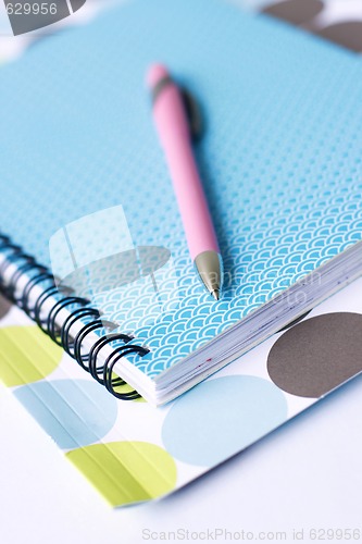 Image of Brightly colored notebook, folder and pen.