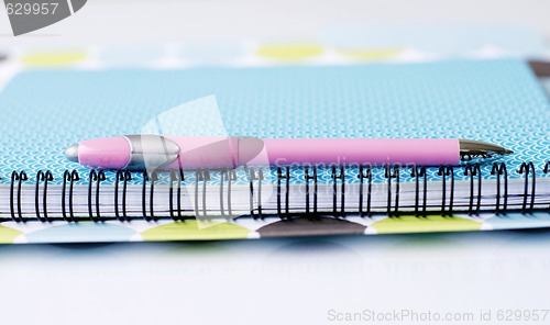 Image of Brightly colored notebook, folder and pen.