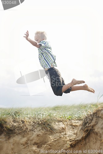 Image of Young boy jumping off a sand dune.