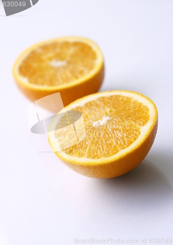Image of Two orange halves on a light surface.
