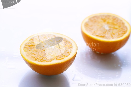 Image of Two orange halves on a light surface.