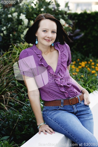 Image of Portrait of a beautiful woman sitting on a fence.