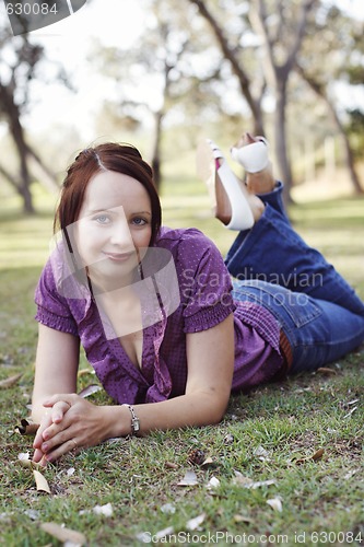 Image of Portrait of a beautiful woman lying on the grass.