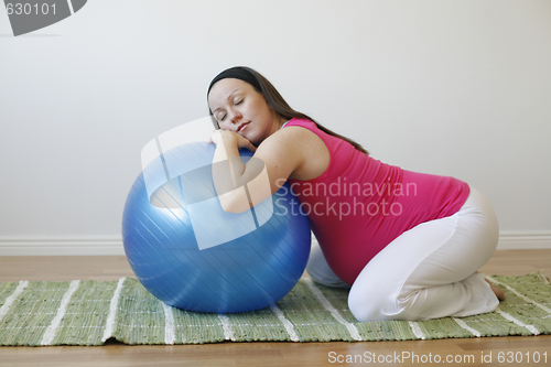 Image of Young pregnant woman doing a relaxation exercise with fitness ba
