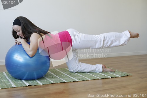 Image of Young pregnant woman doing leg muscle exercise with fitness ball