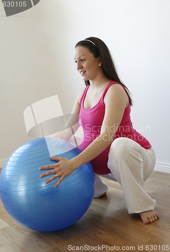 Image of Young smiling pregnant woman doing squatting exercise with fitne