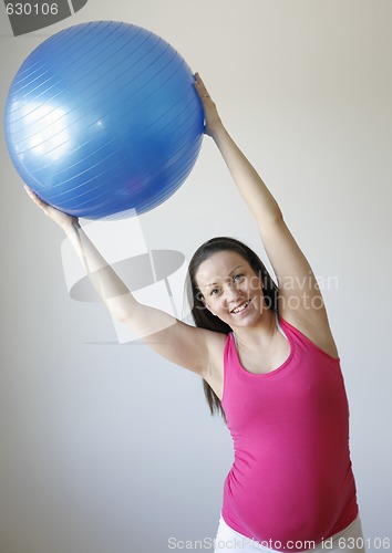 Image of Young smiling pregnant woman exercising with fitness ball.