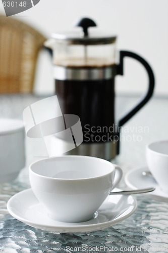 Image of Black filter coffee and plunger on a glass table.