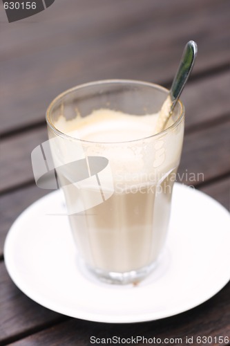 Image of Half empty latte in a glass on a café table.