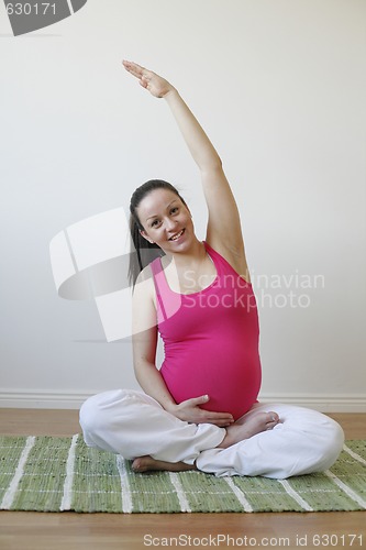 Image of Young pregnant woman doing stretching exercise.