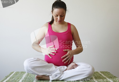 Image of Young thoughtful pregnant woman holding her tummy.