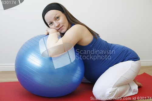 Image of Young pregnant woman doing a relaxation exercise with fitness ba