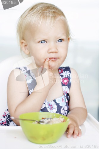 Image of Cute little girl and her breakfast porridge bowl.