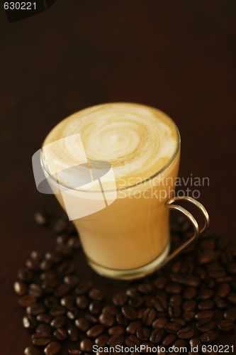 Image of Delicious latte in glass with coffee art swirl design.