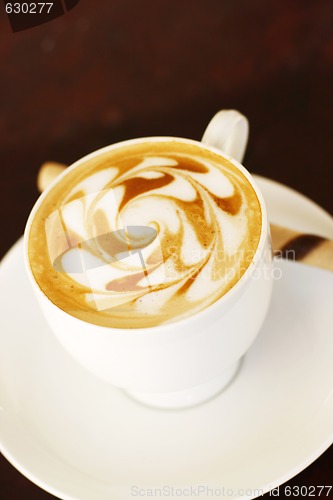 Image of Delicious latte with coffee art swirl design.