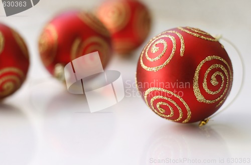 Image of Red Christmas baubles on a glass table.